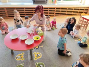 Opiekunka pokazuje dzieciom technikę mieszania kolorów przy pomocy barwników spożywczych