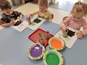 Dzieci odbijają rolką po papierze kolorowe bąbelki