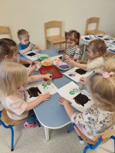 Dzieci odbijają rolką po papierze kolorowe bąbelki