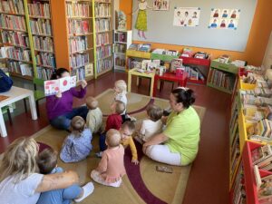 Pani z biblioteki pokazuje i czyta dzieciom książeczkę