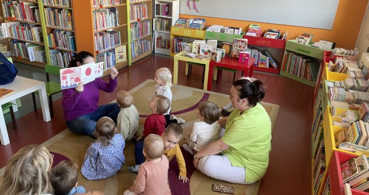 Pani z biblioteki pokazuje i czyta dzieciom książeczkę