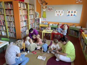 Pani z biblioteki pokazuje i czyta dzieciom książeczkę
