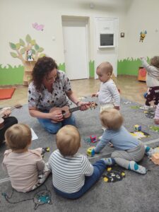 Dzieci z opiekunkami w trakcie zajęć z wykorzystaniem instrumentu ukulele.