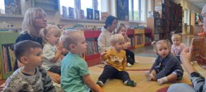 Pani z biblioteki pokazuje i czyta dzieciom książeczkę