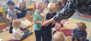 Pani z biblioteki pokazuje i czyta dzieciom książeczkę