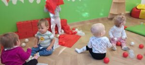 Dzieci bawią się białymi i czerwonymi piłeczkami.