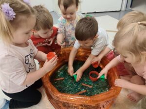 Dzieci bawią się masą przy baseniku sensorycznym