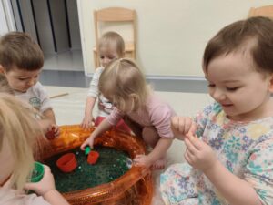Dzieci bawią się masą przy baseniku sensorycznym