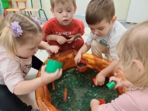 Dzieci bawią się masą przy baseniku sensorycznym