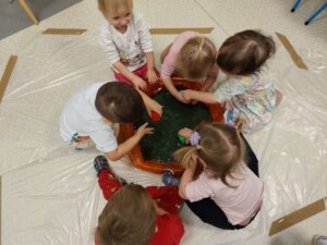 Dzieci bawią się masą przy baseniku sensorycznym