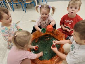 Dzieci bawią się masą przy baseniku sensorycznym