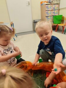 Dzieci bawią się masą przy baseniku sensorycznym