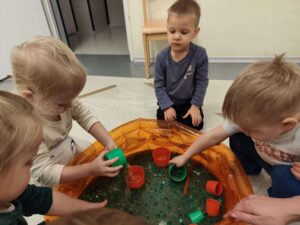 Dzieci bawią się masą przy baseniku sensorycznym