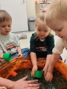 Dzieci bawią się masą przy baseniku sensorycznym
