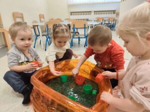 Dzieci bawią się masą przy baseniku sensorycznym