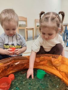 Dzieci bawią się masą przy baseniku sensorycznym
