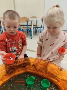 Dzieci bawią się masą przy baseniku sensorycznym