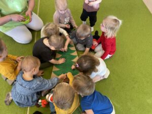 Dzieci wkładają kolorowe patyczki do uszu w karton choinki