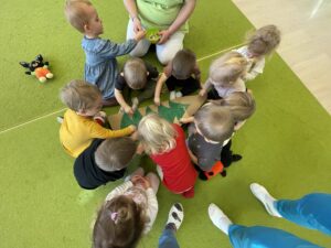 Dzieci wkładają kolorowe patyczki do uszu w karton choinki