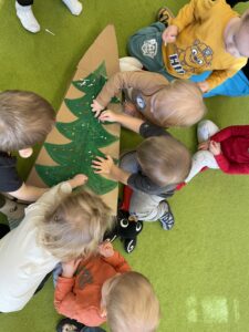 Dzieci wkładają kolorowe patyczki do uszu w karton choinki