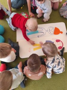 Dzieci wyklejają ubranka zimowe na postaciach dziewczynki i chłopczyka