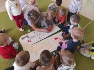 Dzieci wyklejają ubranka zimowe na postaciach dziewczynki i chłopczyka