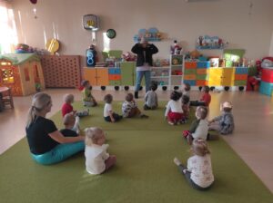 Opiekunka prezentuje dzieciom ubranie zimowe.