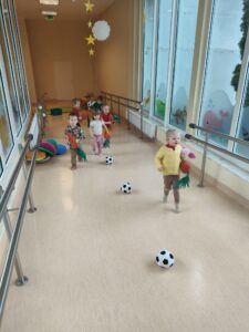 Dzieci trzymając pluszowe marchewki pokonują slalom z piłek