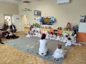 Dzieci i ciocie ubrane całe na biało grają na instrumentach