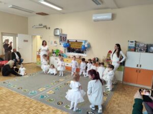 Dzieci ubrane całe na biało tańczą na dywanie