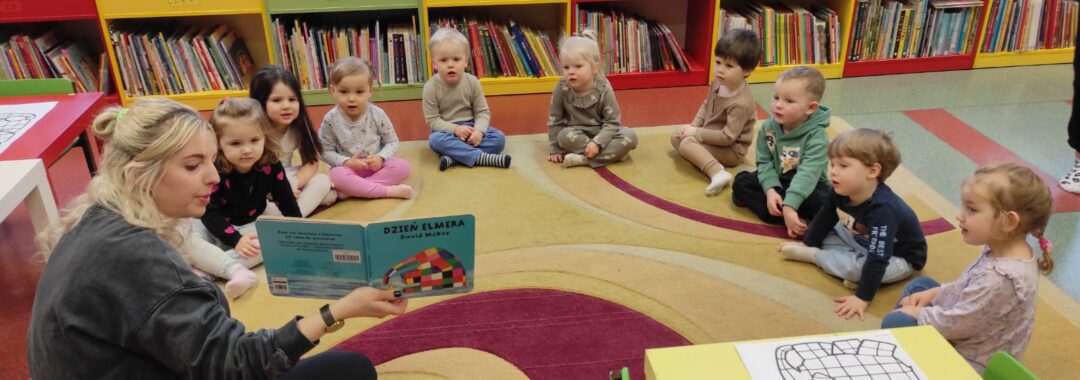 Dzieci w bibliotece słuchają książki czytanej przez panią