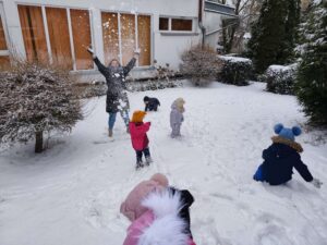 Dzieci wraz ciocią podrzucają śnieg