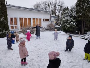Dzieci wraz ciocią podrzucają śnieg