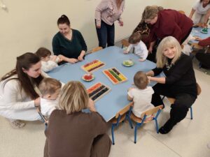 Dzieci wraz z dziadkami robią korale z kolorowego makaronu