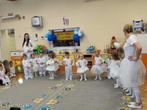 Dzieci w białych strojach tańczą na dywanie
