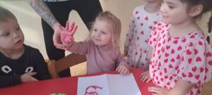Dzieci odbijają rączkę pomalowaną różową farbą