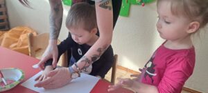 Dzieci odbijają rączkę pomalowaną różową farbą