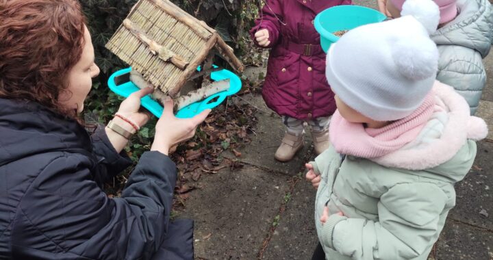 Ciocia pokazuje dzieciom karmnik