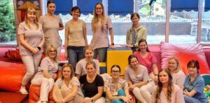 Grupa opiekunów żłobka siedzących i stojących w sali zabaw, po zakończonym szkoleniu dotyczącym współpracy z rodzicami na rzecz dziecka