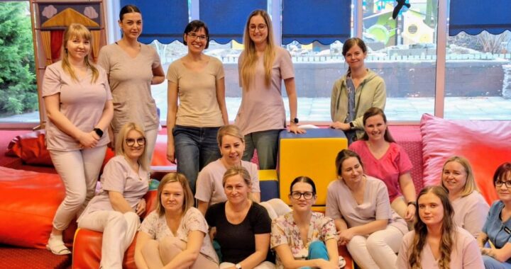 Grupa opiekunów żłobka siedzących i stojących w sali zabaw, po zakończonym szkoleniu dotyczącym współpracy z rodzicami na rzecz dziecka