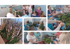 Pracownicy żłobka wspólnie przygotowują palmy wielkanocne – siedzą przy stole i układają gałązki bazi, bukszpanu oraz kolorowe wstążki. Na zdjęciach widoczne są etapy tworzenia palm oraz gotowe, bogato zdobione kompozycje