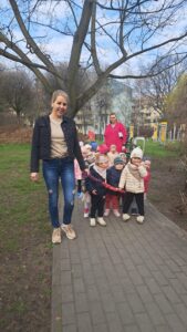 Dzieci z opiekunem wracają z placu zabaw trzymając węża spacerowego