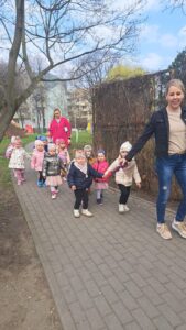 Dzieci z opiekunem wracają z placu zabaw trzymając węża spacerowego