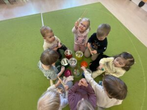 Dzieci za pomocą drewnianych szczypiec wkładają kolorowe pompony do odpowiednich pojemników