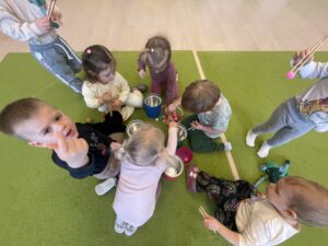 Dzieci za pomocą drewnianych szczypiec wkładają kolorowe pompony do odpowiednich pojemników