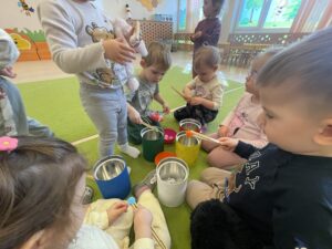 Dzieci za pomocą drewnianych szczypiec wkładają kolorowe pompony do odpowiednich pojemników