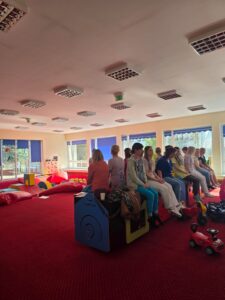 Część praktyczna szkolenia – fizjoterapeutka pokazuje opiekunom prawidłowe ułożenie ciała i postawę podczas pracy z dzieckiem.