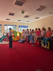 Część praktyczna szkolenia – fizjoterapeutka pokazuje opiekunom prawidłowe ułożenie ciała i postawę podczas pracy z dzieckiem.