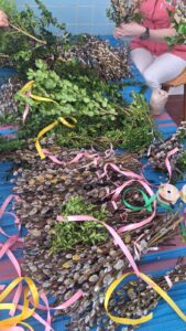 Gotowe i przygotowywane palmy wielkanocne ułożone na stole podczas pracy zespołowej.