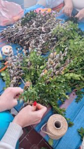 Gotowe i przygotowywane palmy wielkanocne ułożone na stole podczas pracy zespołowej.